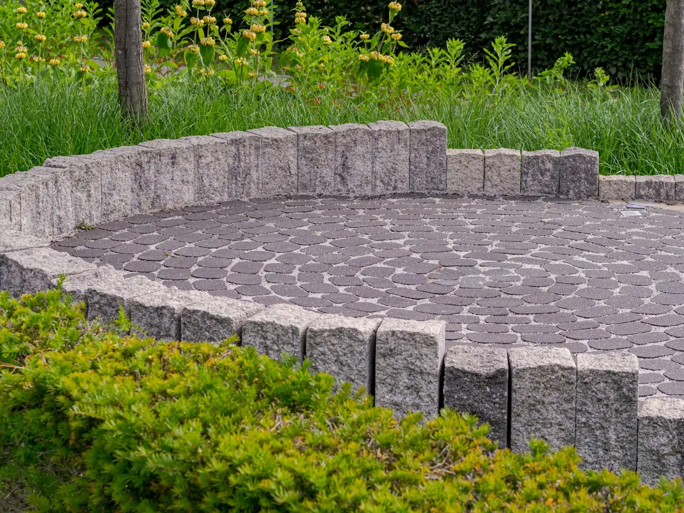 A circular paver patio with a low stone wall
